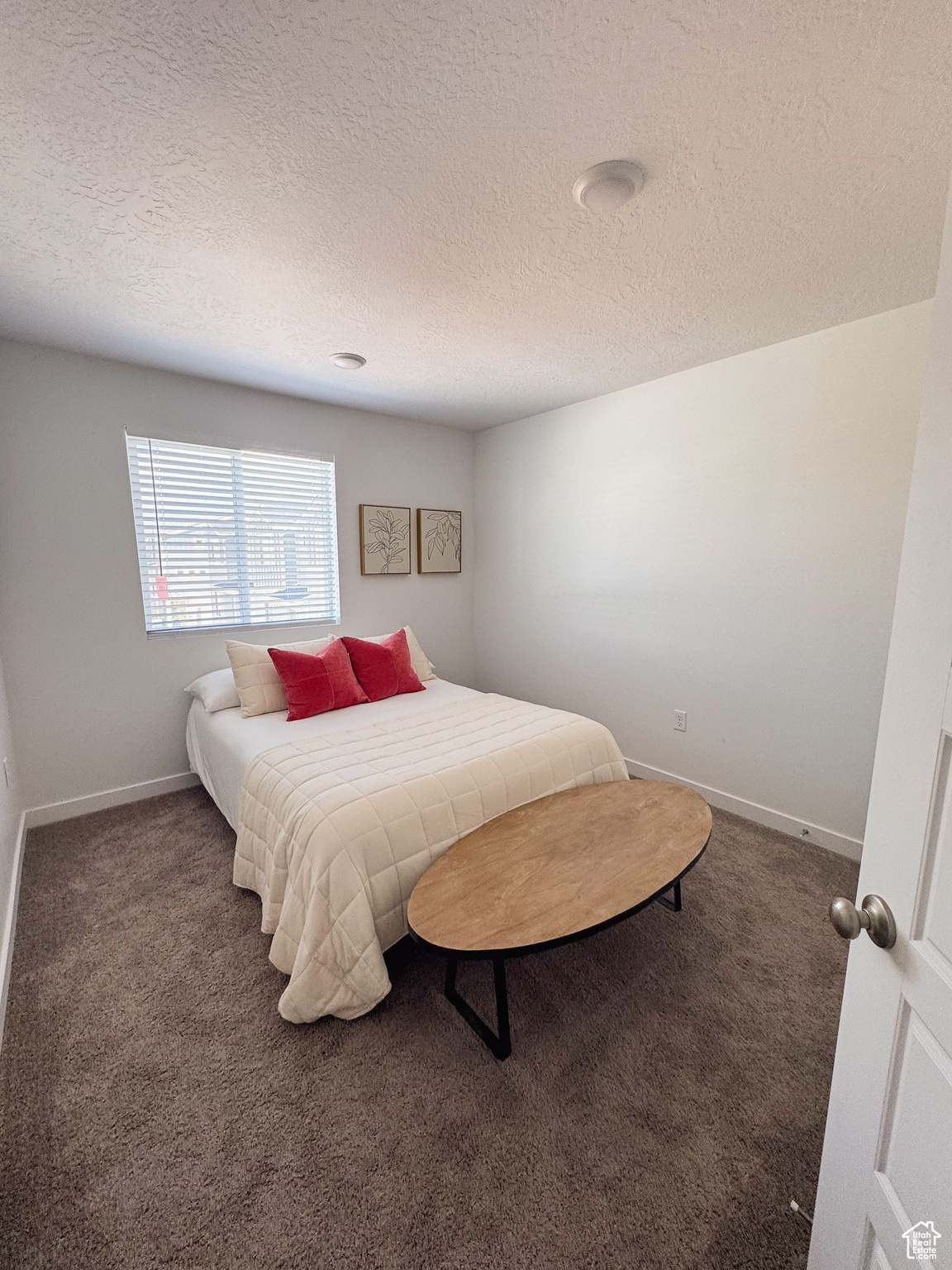 Bedroom featuring dark carpet and a textured ceiling