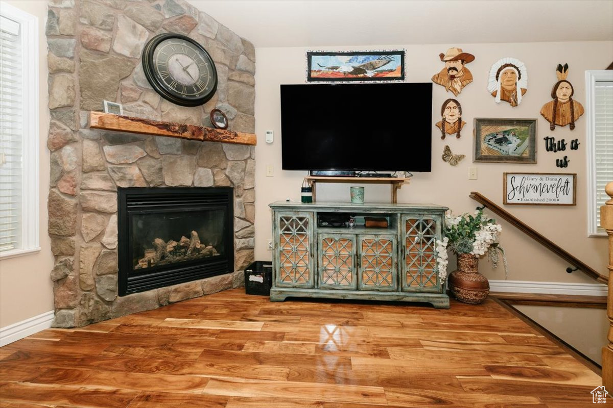 Living room with a stone fireplace and hardwood / wood-style flooring