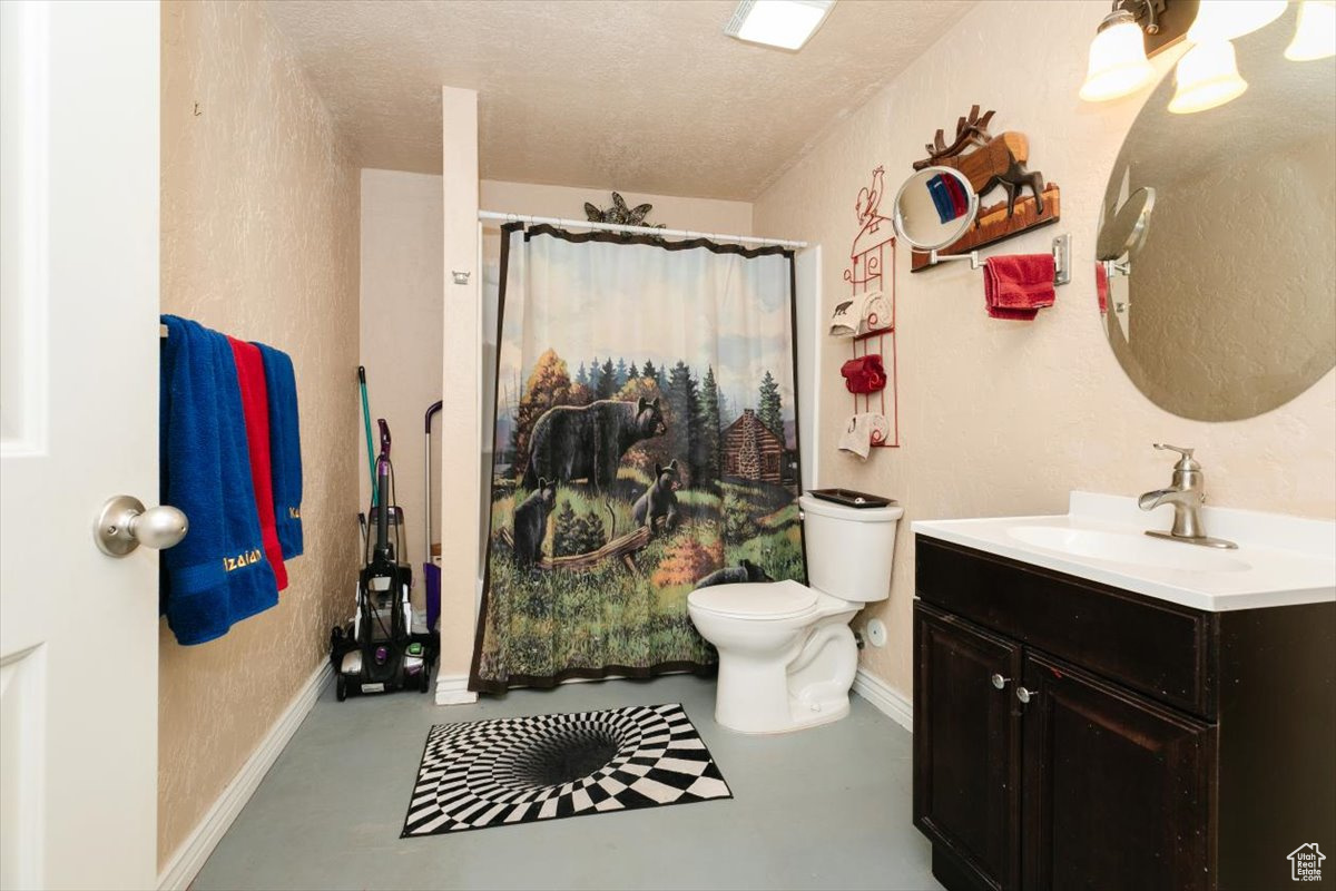 Bathroom with vanity, concrete floors, a textured ceiling, and toilet