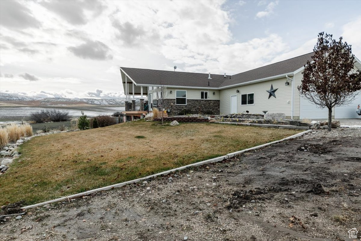 Back of house with a lawn and a water view