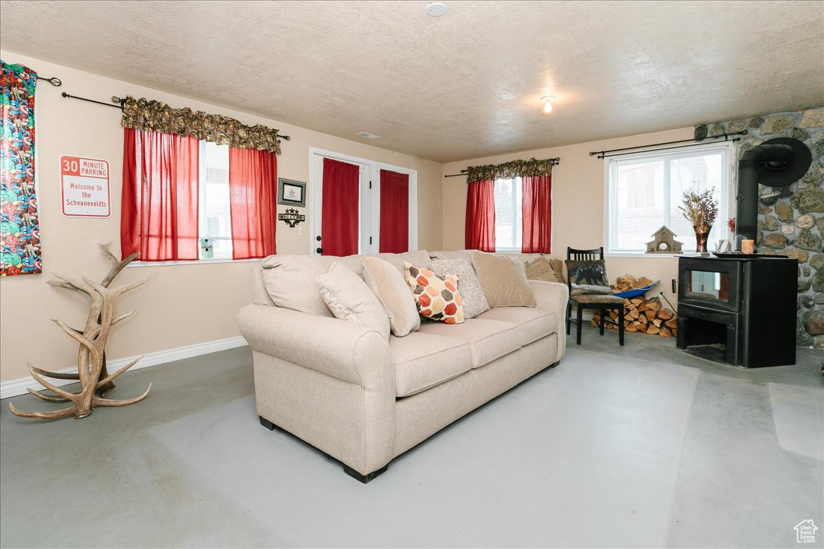 Living room featuring a wood stove, a wealth of natural light, and concrete flooring