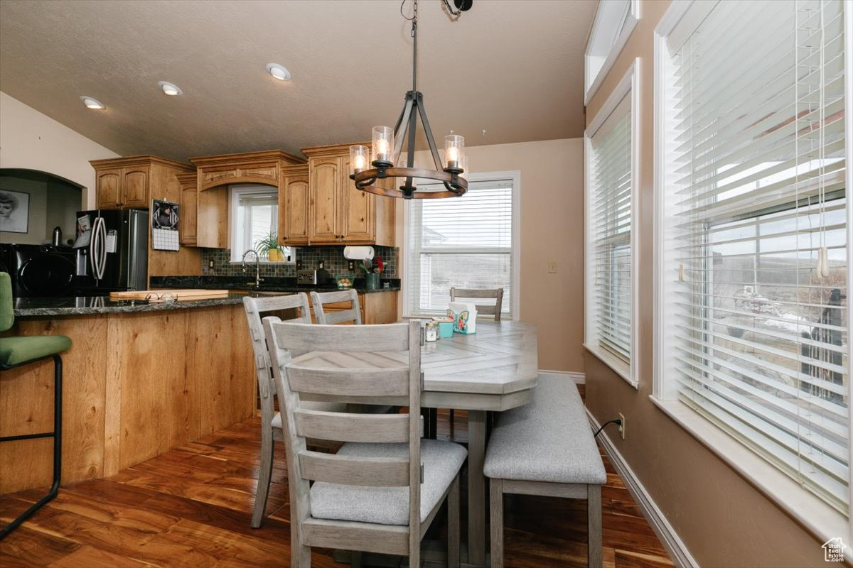 Dining area featuring a healthy amount of sunlight, dark wood-type flooring, and an inviting chandelier