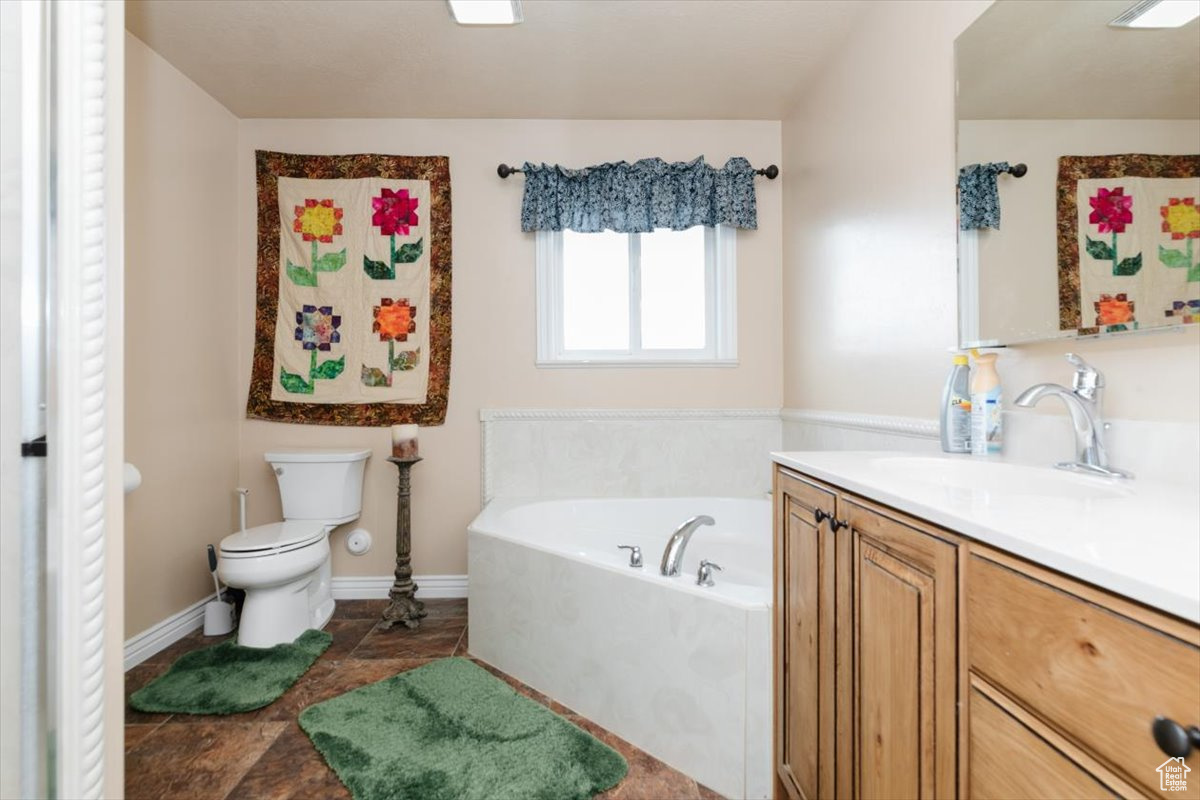 Bathroom with a tub, vanity, and toilet