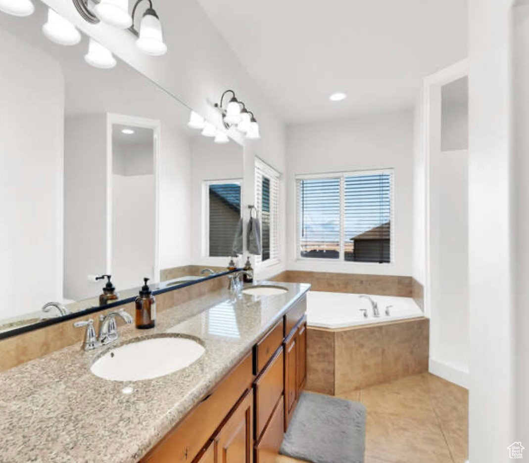 Bathroom featuring tiled bath, tile patterned flooring, and vanity