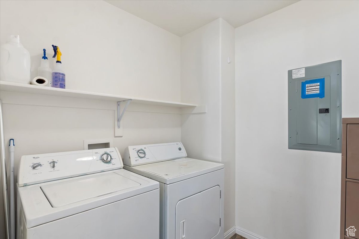 Clothes washing area featuring electric panel and washer and dryer