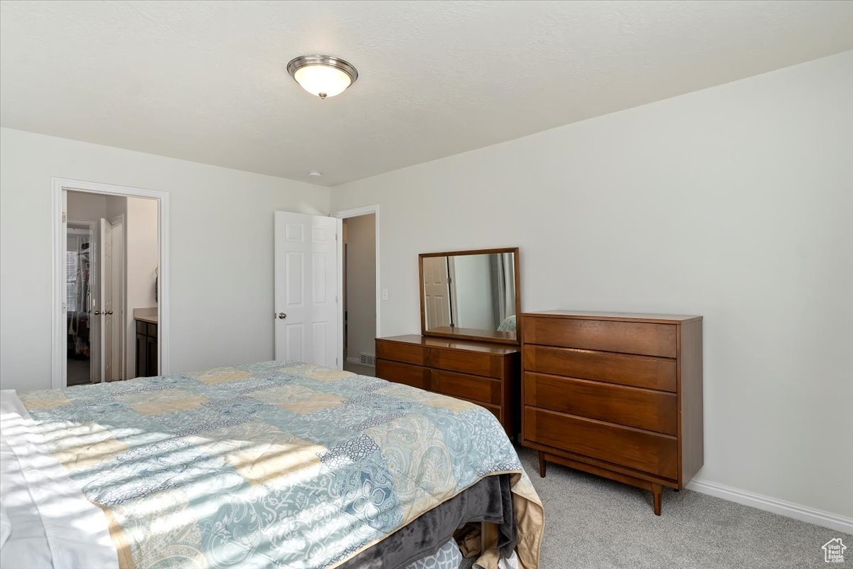 Bedroom featuring connected bathroom and light colored carpet