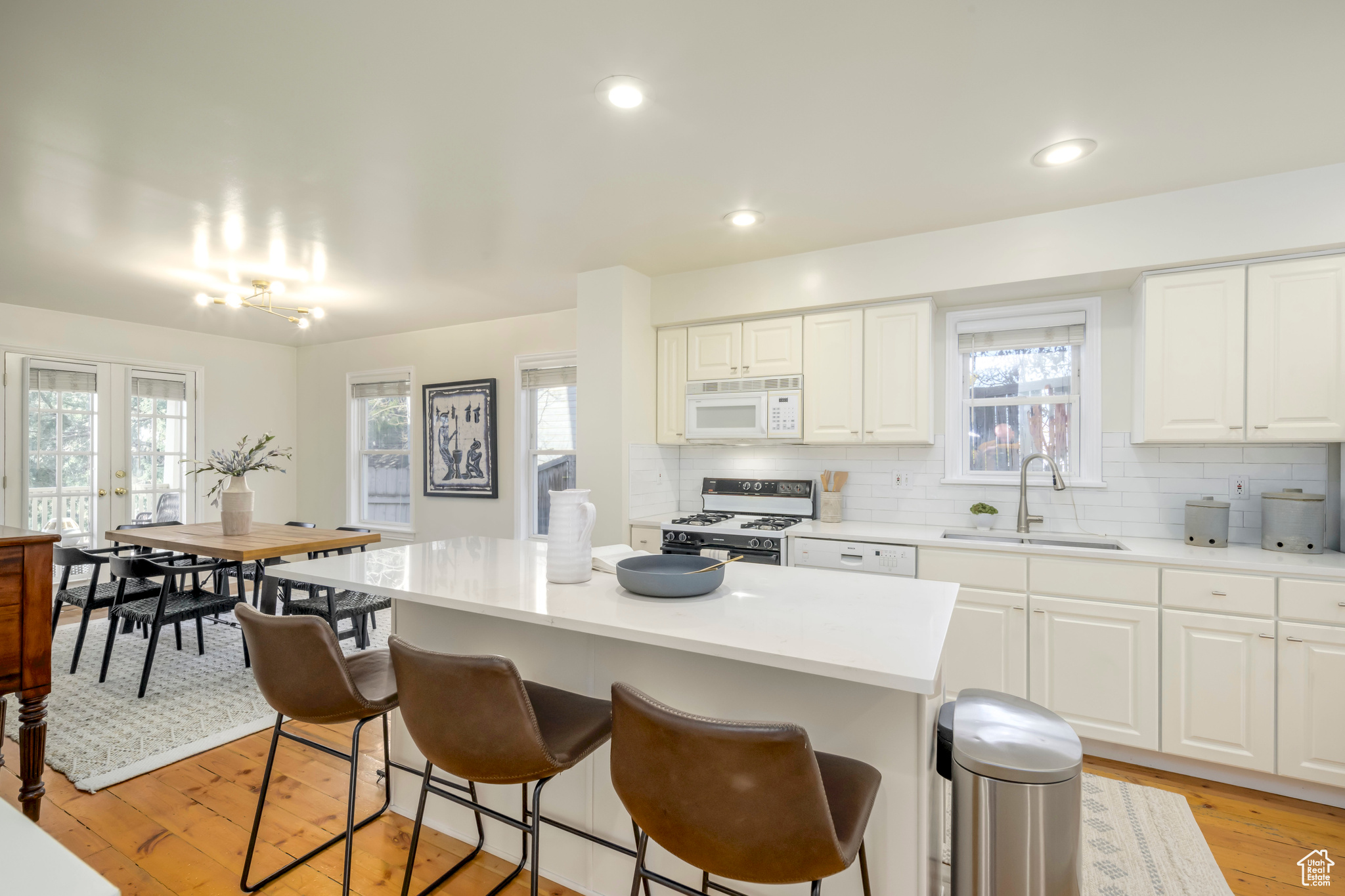 Kitchen with white cabinets, white appliances, a center island, and sink