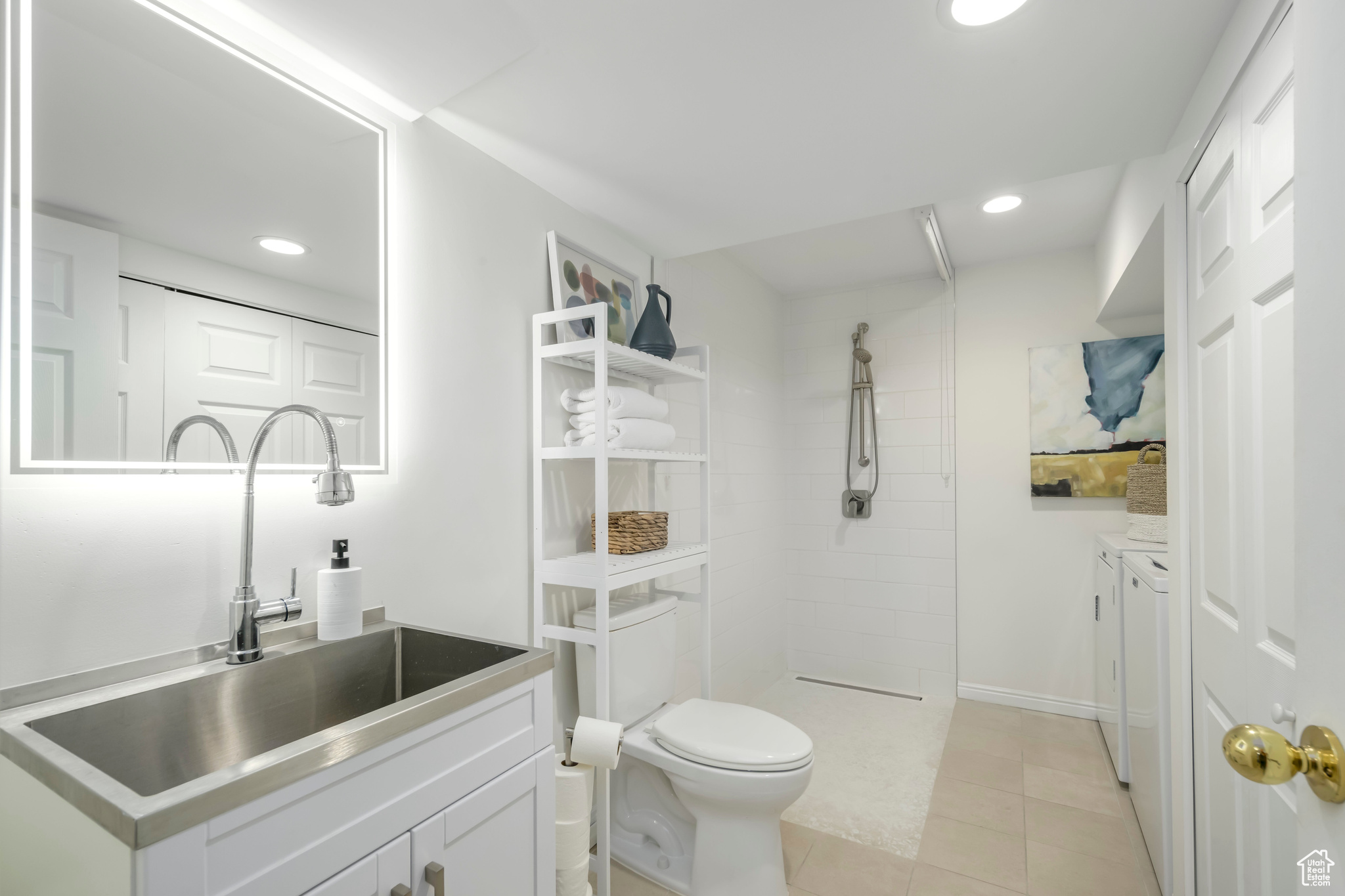 New basement bathroom featuring toilet, a tile shower, vanity, and heated tile patterned floors