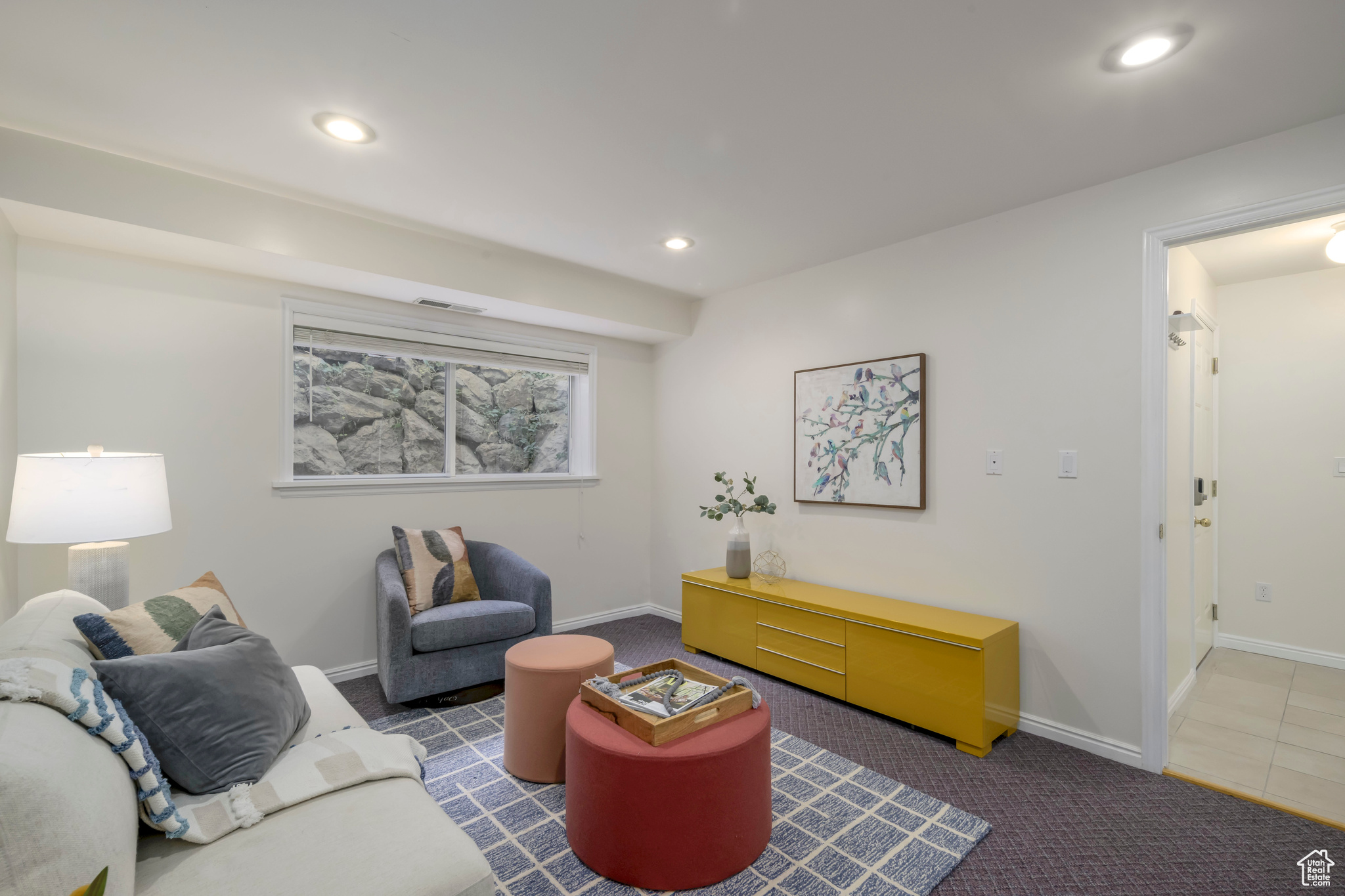 Basement living room with dark colored carpet