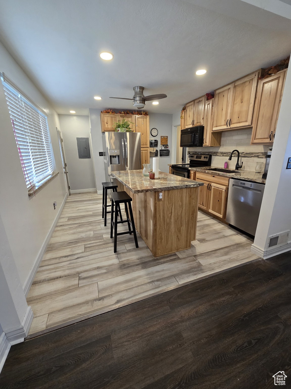 Kitchen featuring sink, a center island, light stone counters, light hardwood / wood-style flooring, and appliances with stainless steel finishes