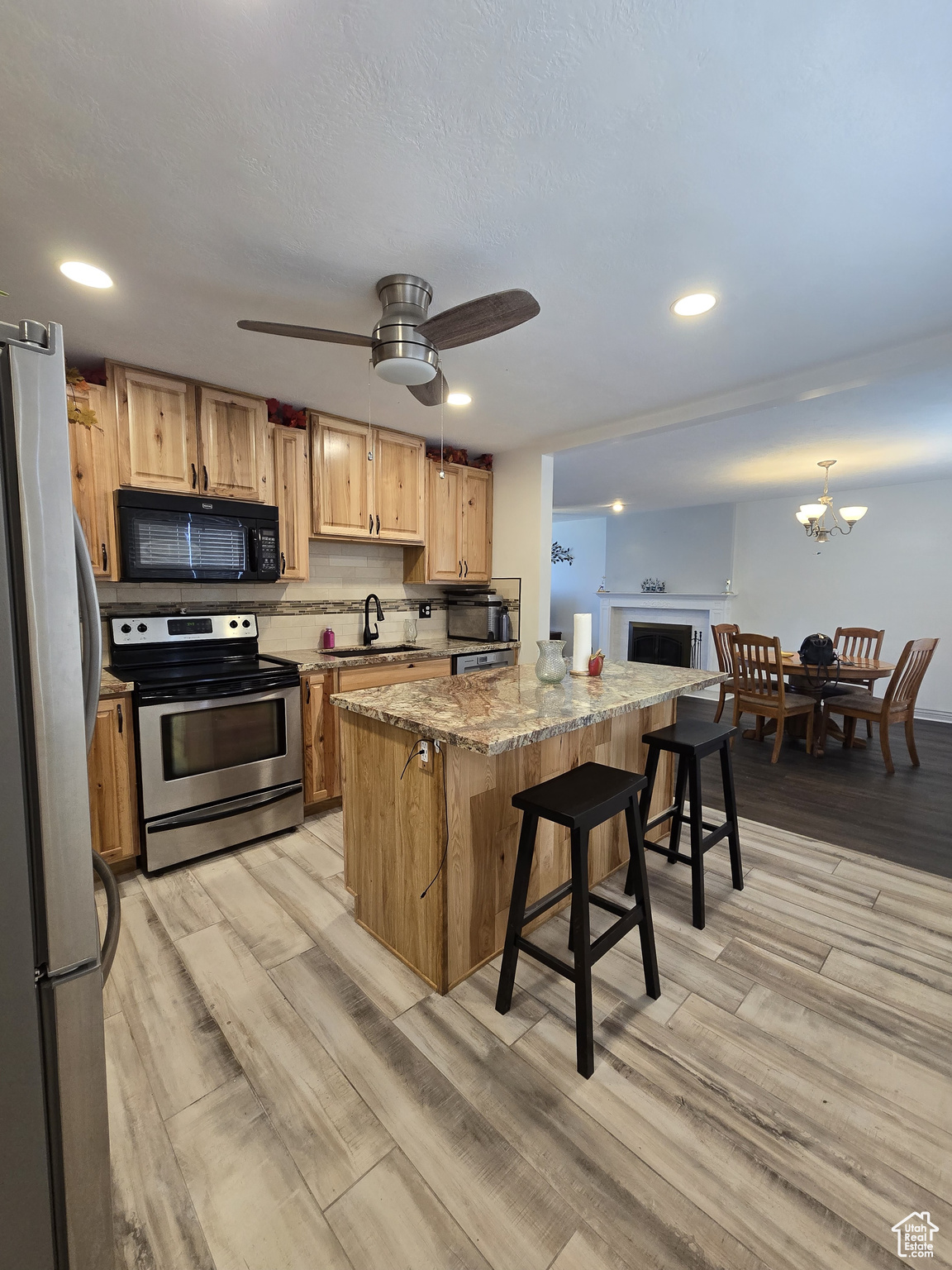 Kitchen featuring ceiling fan with notable chandelier, stainless steel appliances, sink, a kitchen island, and a breakfast bar area