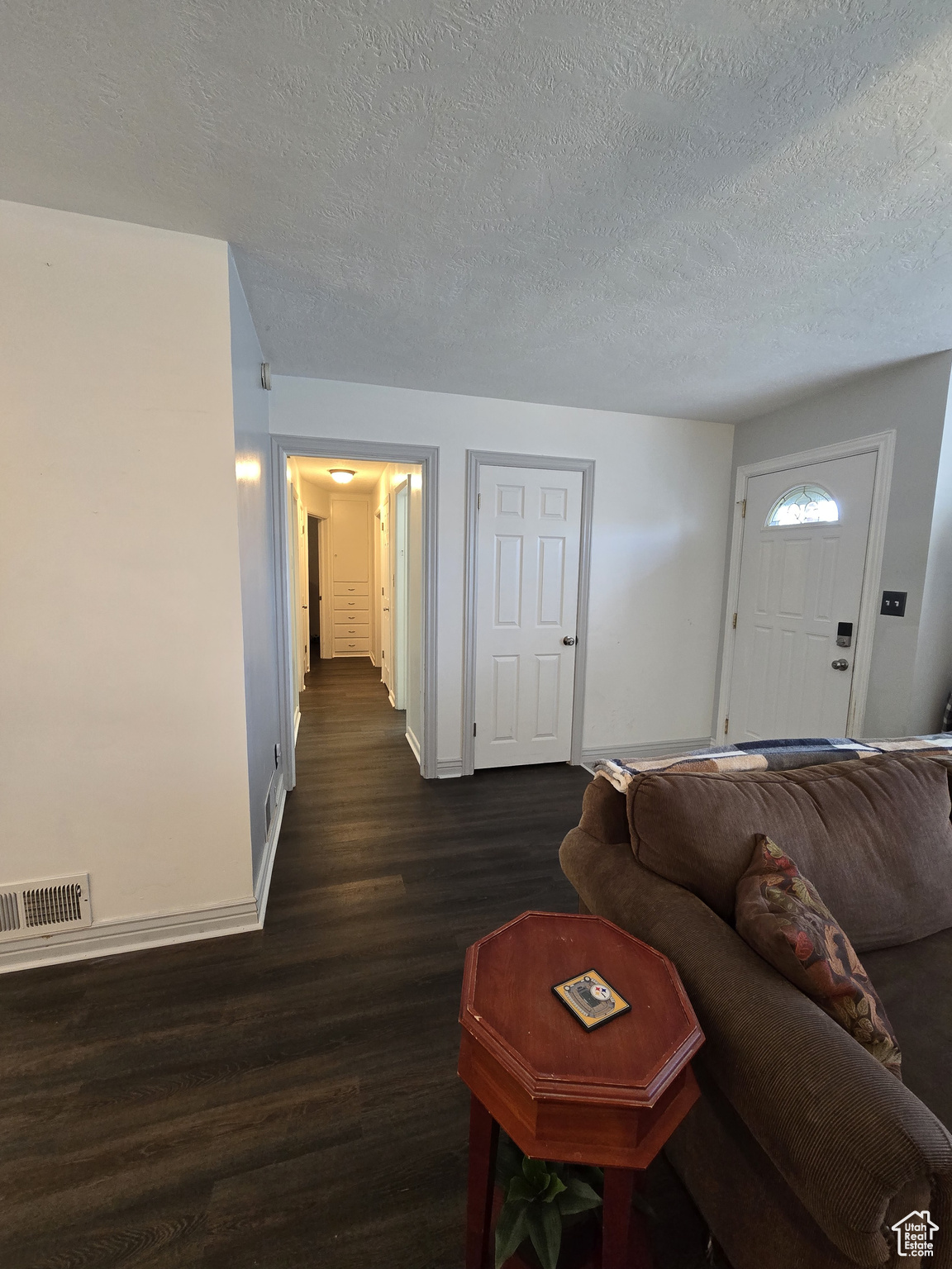 Living room with a textured ceiling and dark hardwood / wood-style floors