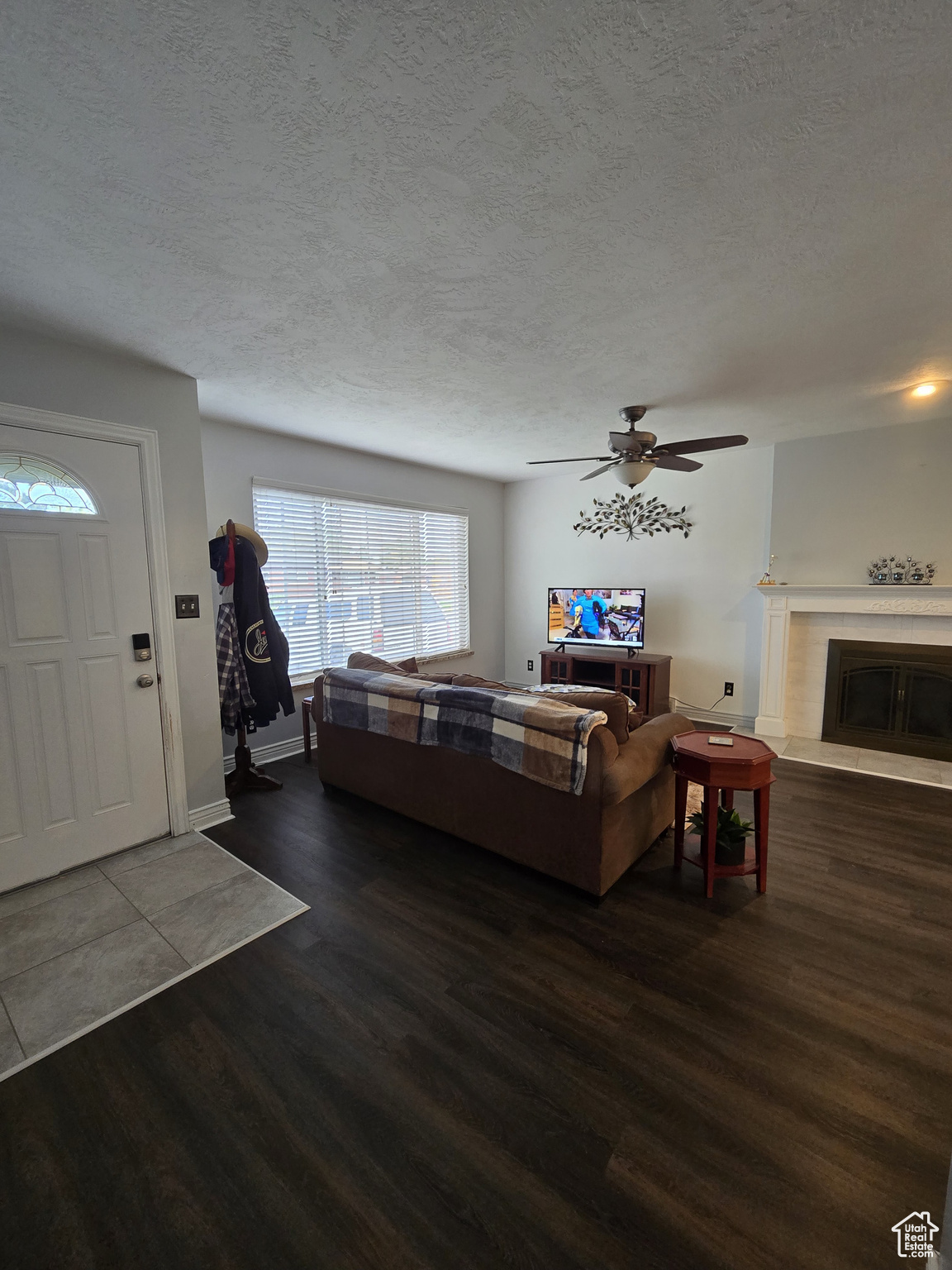 Living room with ceiling fan, dark hardwood / wood-style floors, and a textured ceiling