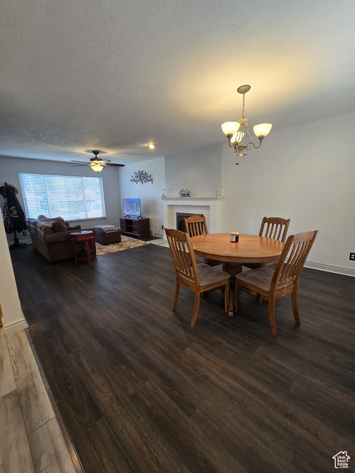 Dining space featuring dark wood-type flooring and ceiling fan with notable chandelier