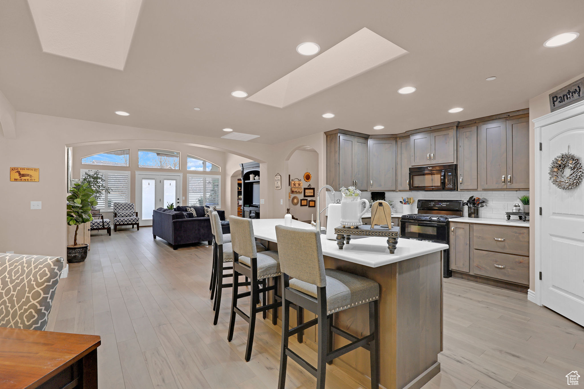 Kitchen featuring black appliances, a breakfast bar, light hardwood / wood-style floors, and a center island with sink