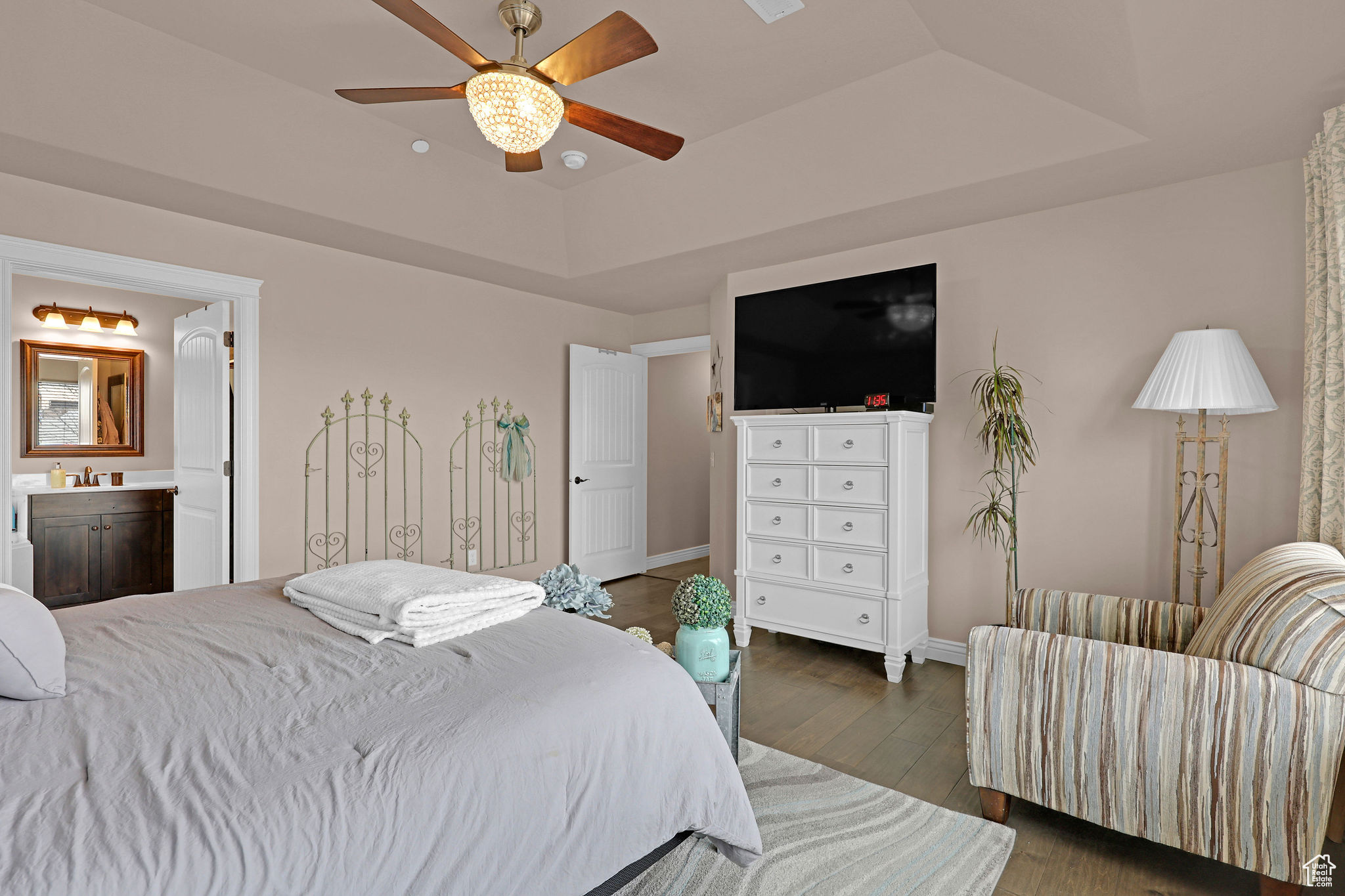 Bedroom featuring connected bathroom, ceiling fan, sink, a raised ceiling, and dark hardwood / wood-style floors