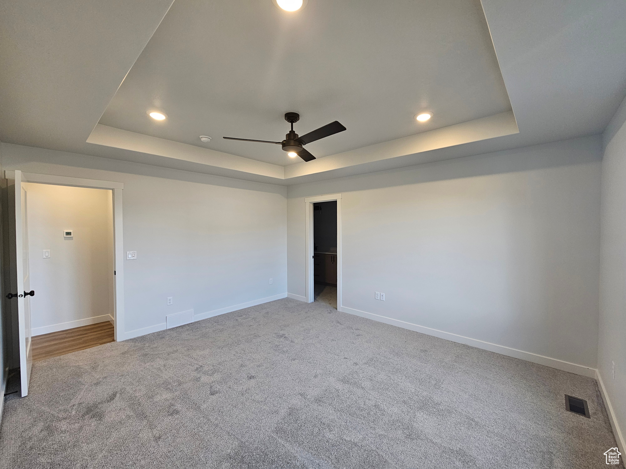 Unfurnished room with carpet floors, a tray ceiling, and ceiling fan