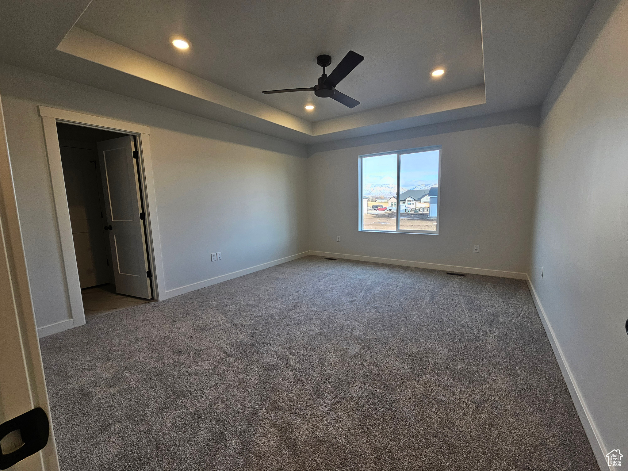 Carpeted spare room with a raised ceiling and ceiling fan