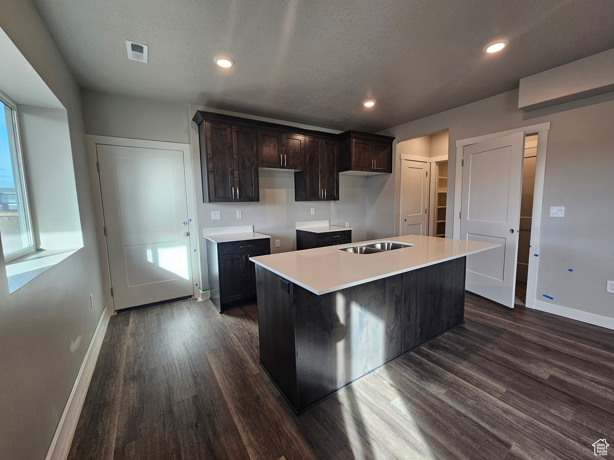 Kitchen featuring a textured ceiling, dark brown cabinetry, sink, dark hardwood / wood-style floors, and a kitchen island