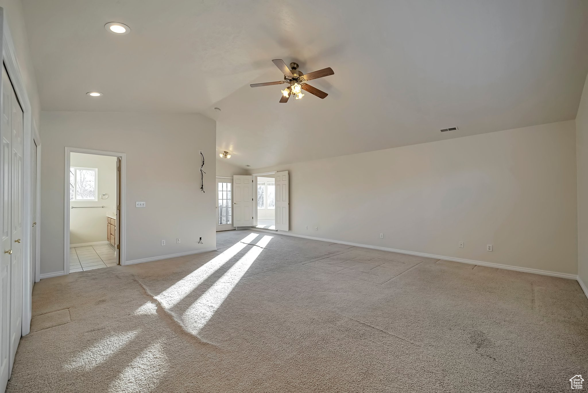 Spare room with light colored carpet, vaulted ceiling, and ceiling fan