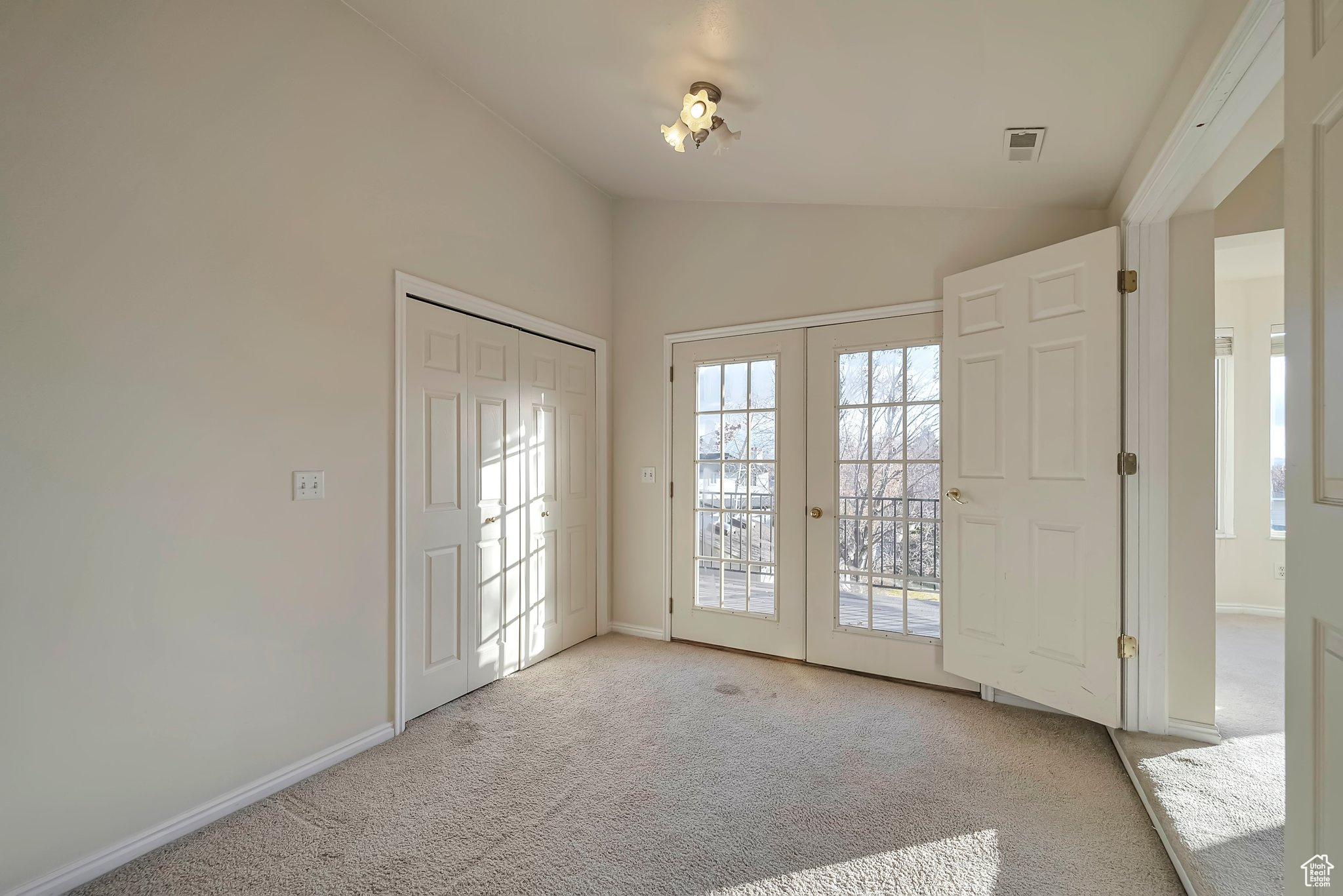 Entryway featuring vaulted ceiling, light carpet, and french doors