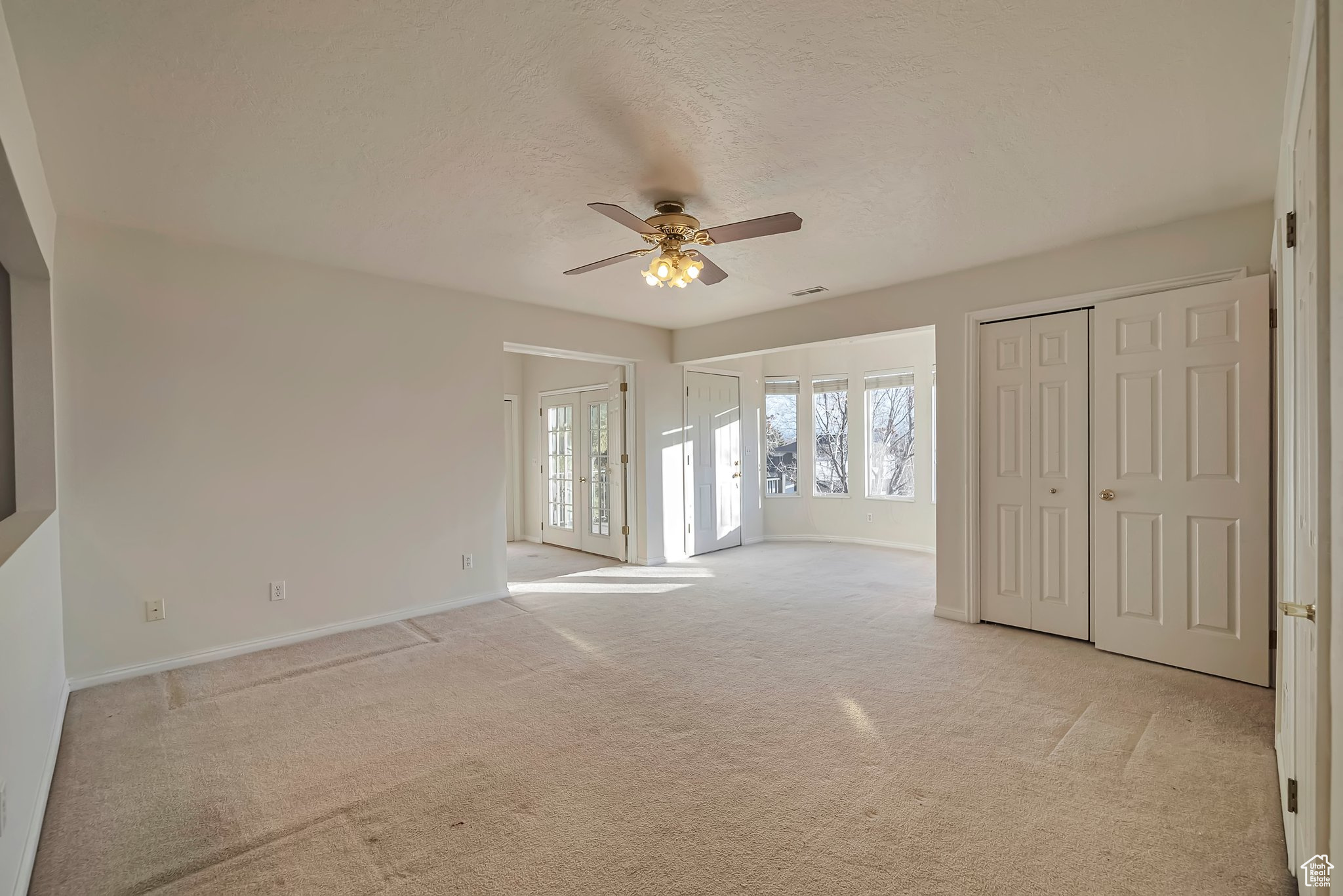 Carpeted empty room with french doors and ceiling fan