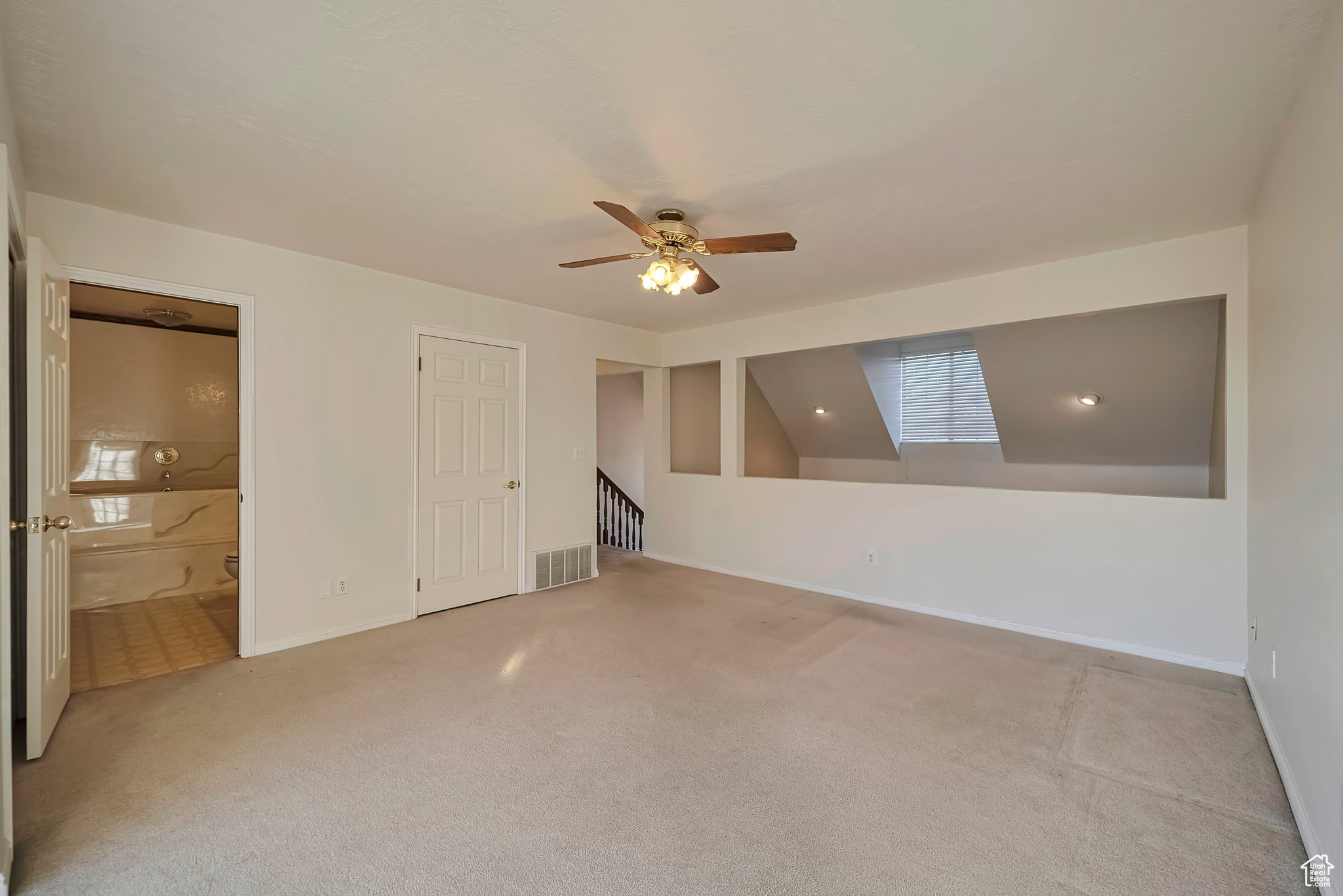 Empty room with ceiling fan and light colored carpet