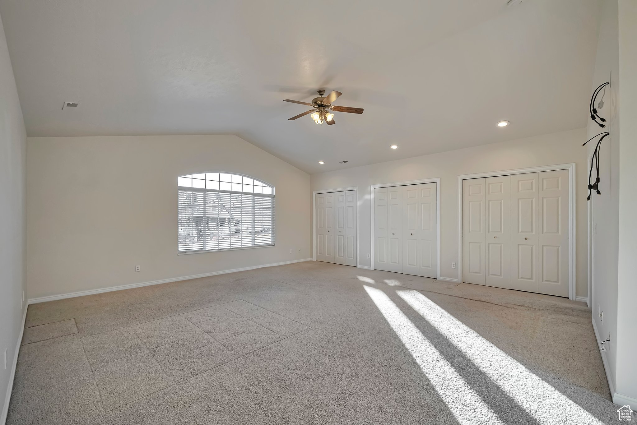 Carpeted empty room with ceiling fan and lofted ceiling