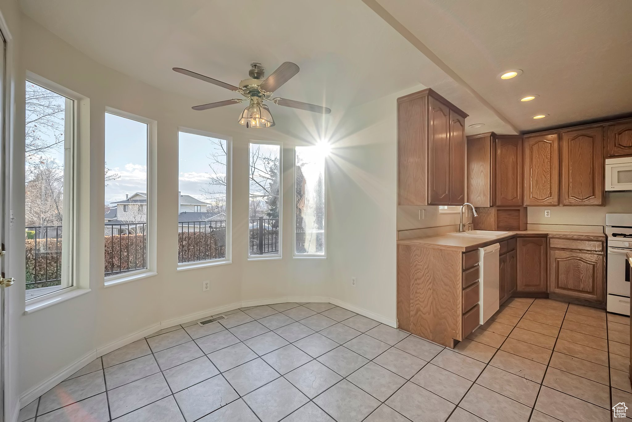 Kitchen featuring ceiling fan, sink, light tile patterned flooring, and white appliances