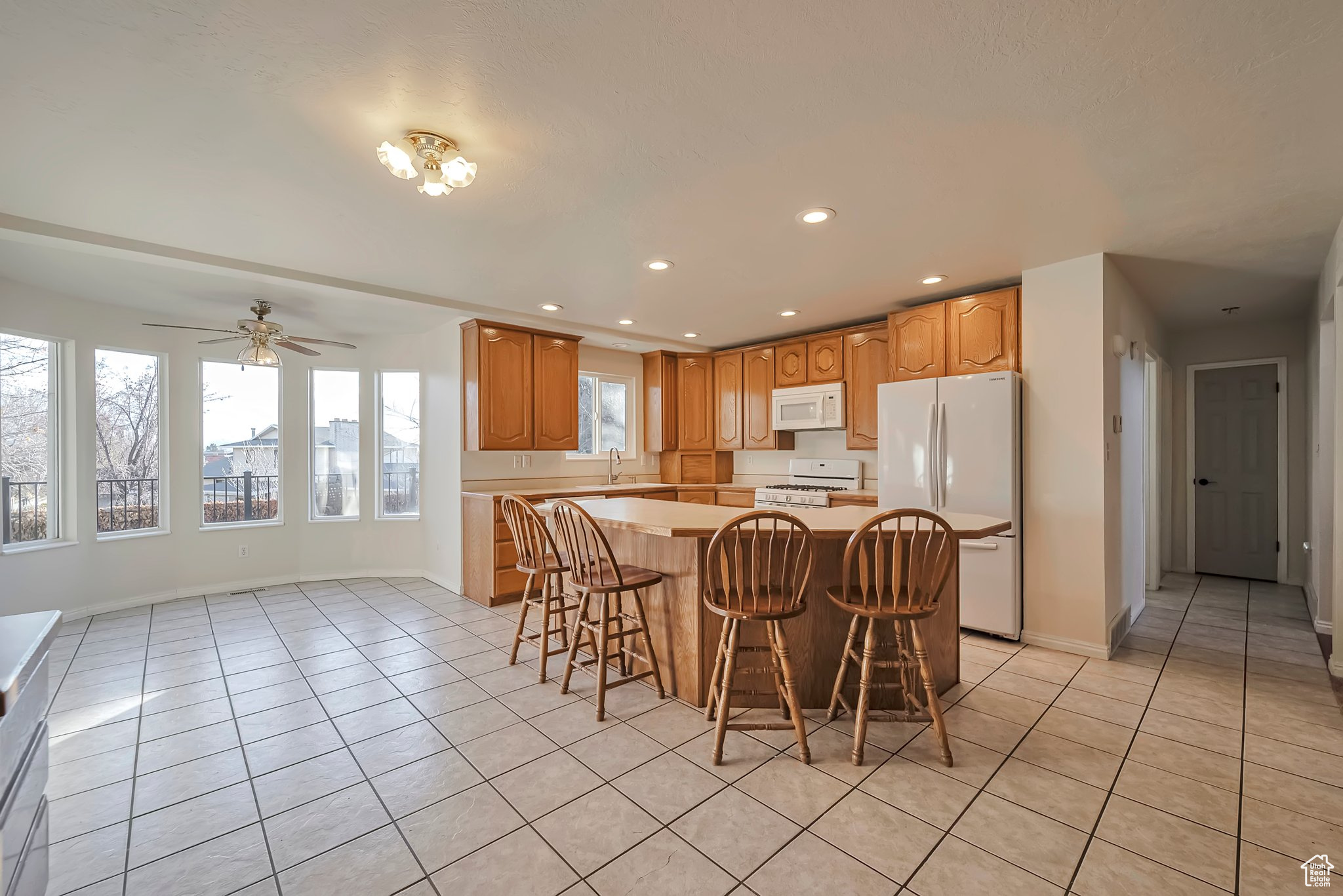 Kitchen featuring sink, a kitchen island, white appliances, a kitchen bar, and light tile patterned floors