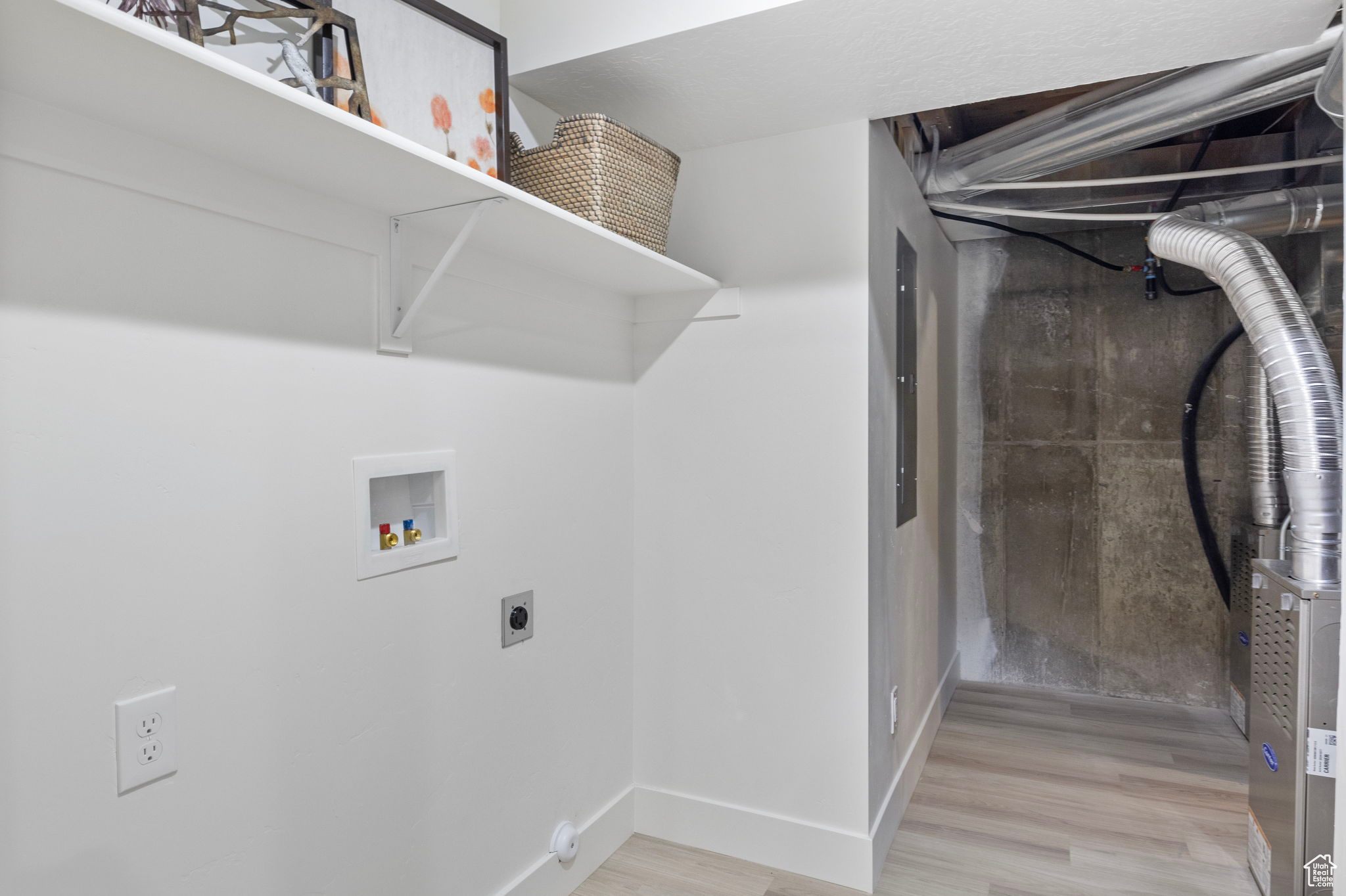 Basement washroom with electric dryer hookup, hookup for a washing machine, and light LVP floors