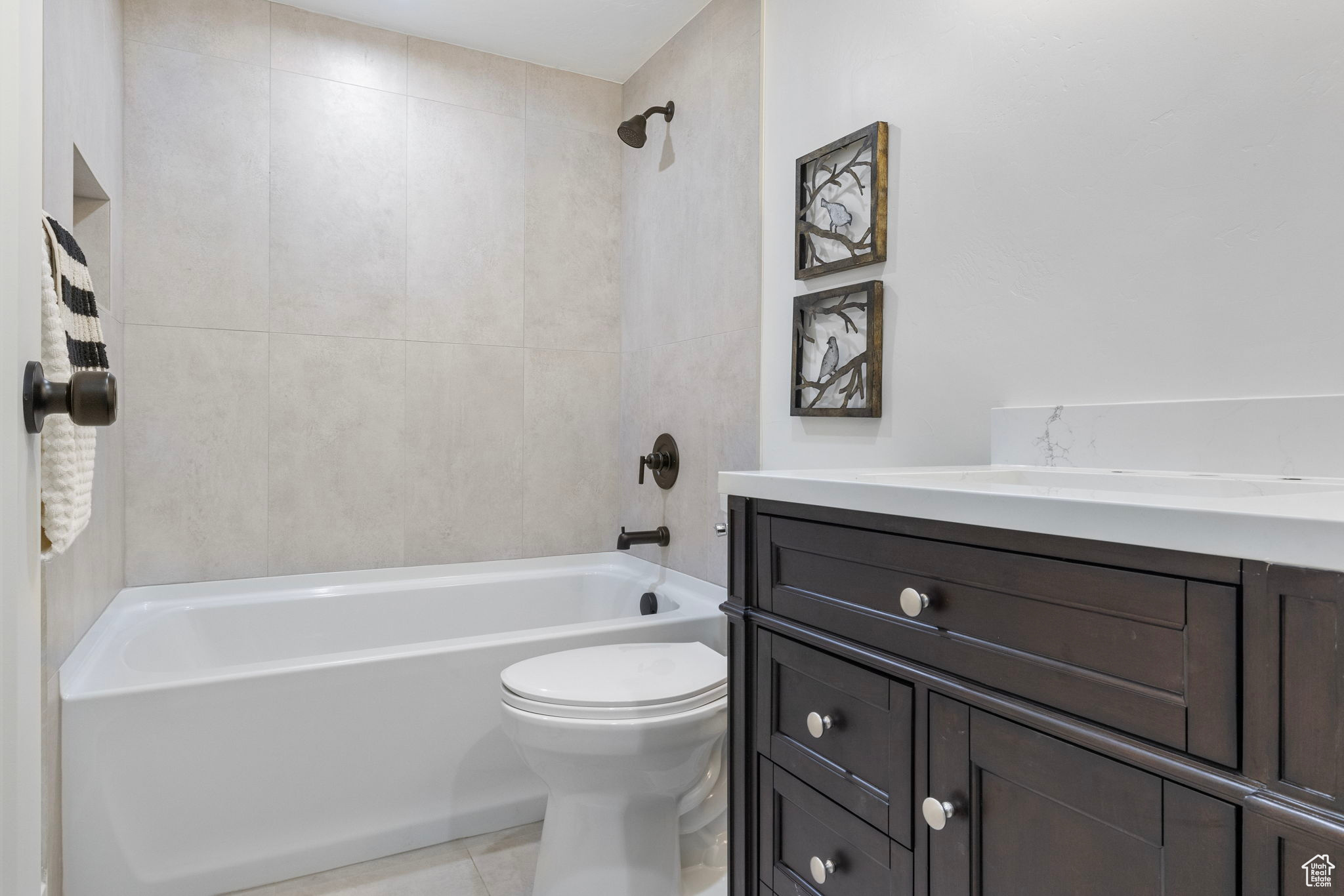 Full basement bathroom featuring tiled shower / bath, tile patterned flooring, vanity, and toilet