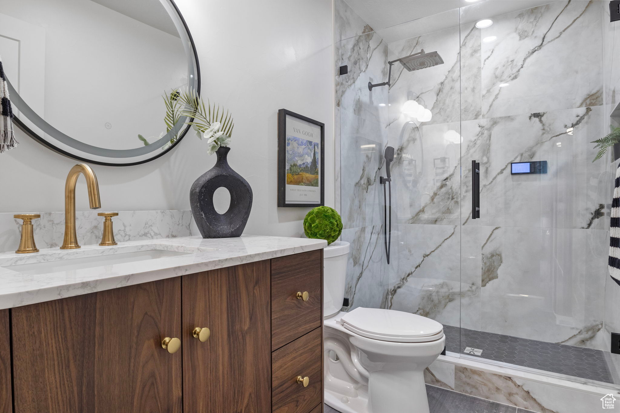 Primary Bathroom with quartz top vanity, toilet, and custom stone shower with shower door