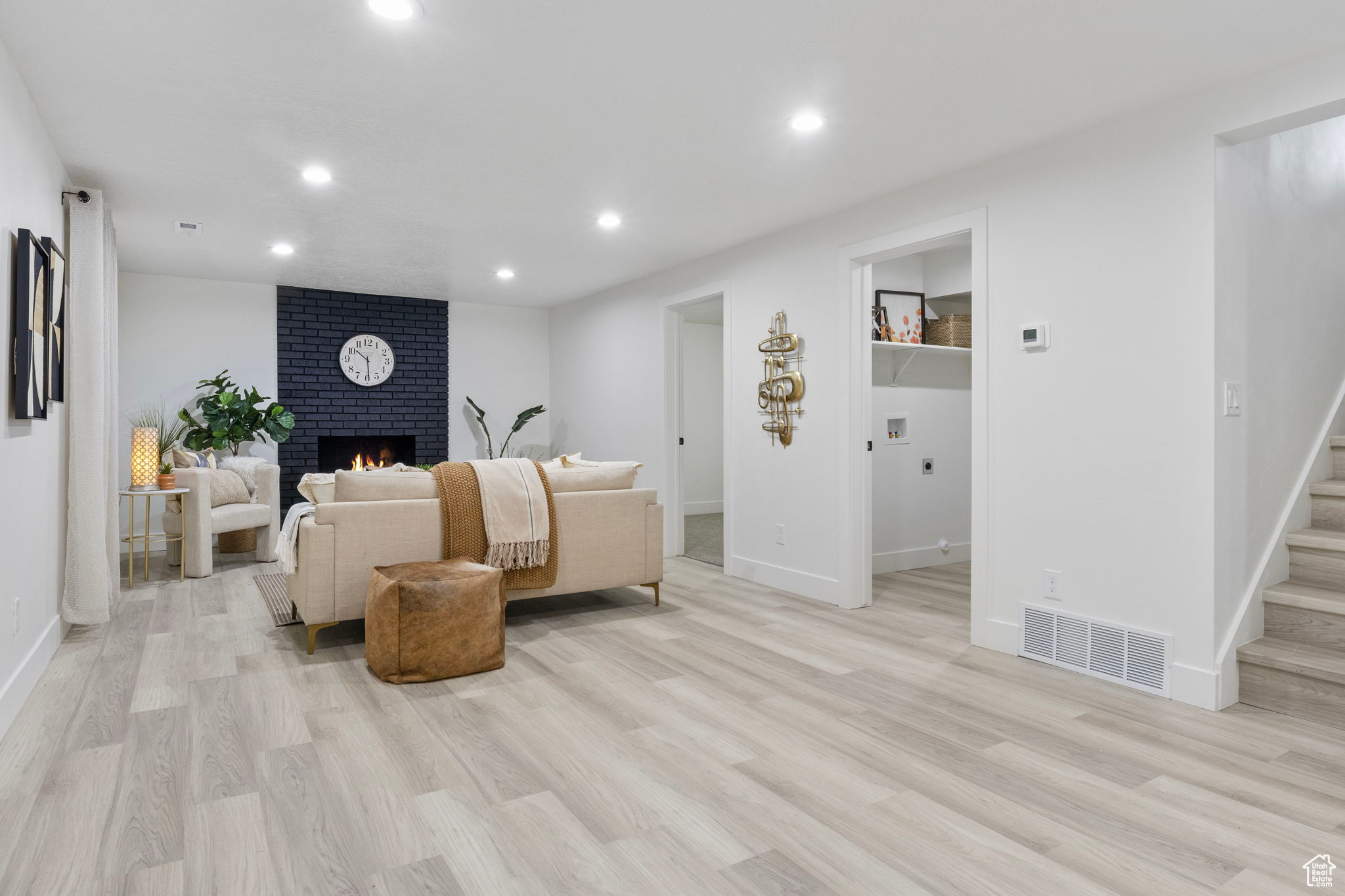 Living room featuring light luxury vinyl plank floors and wood burning fireplace with brick surround.