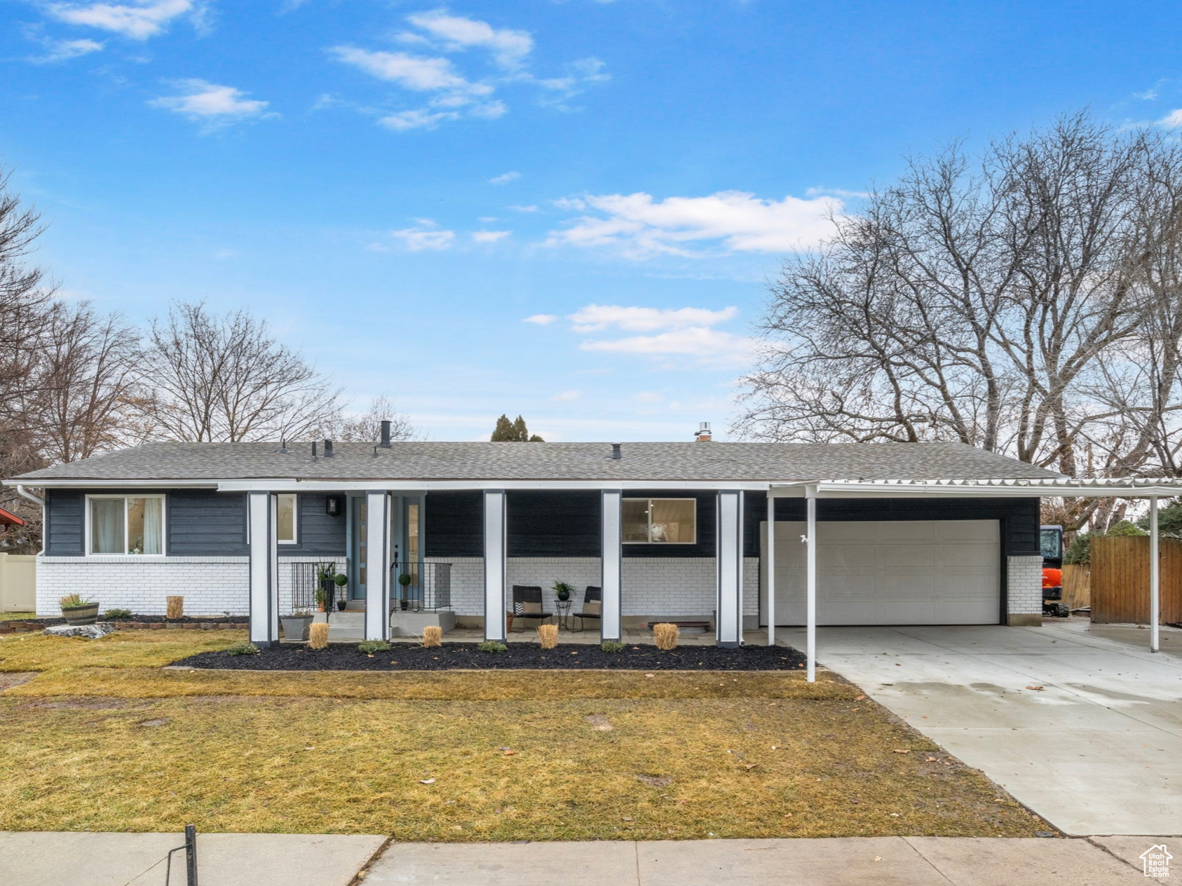 Ranch-style house featuring a porch, a garage, and a front lawn