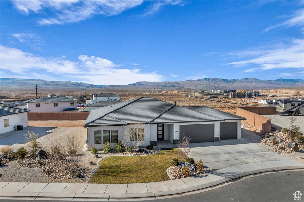 Single story home featuring a mountain view, a front lawn, and a garage