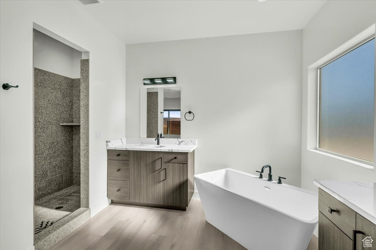 Bathroom featuring plus walk in shower, wood-type flooring, and vanity