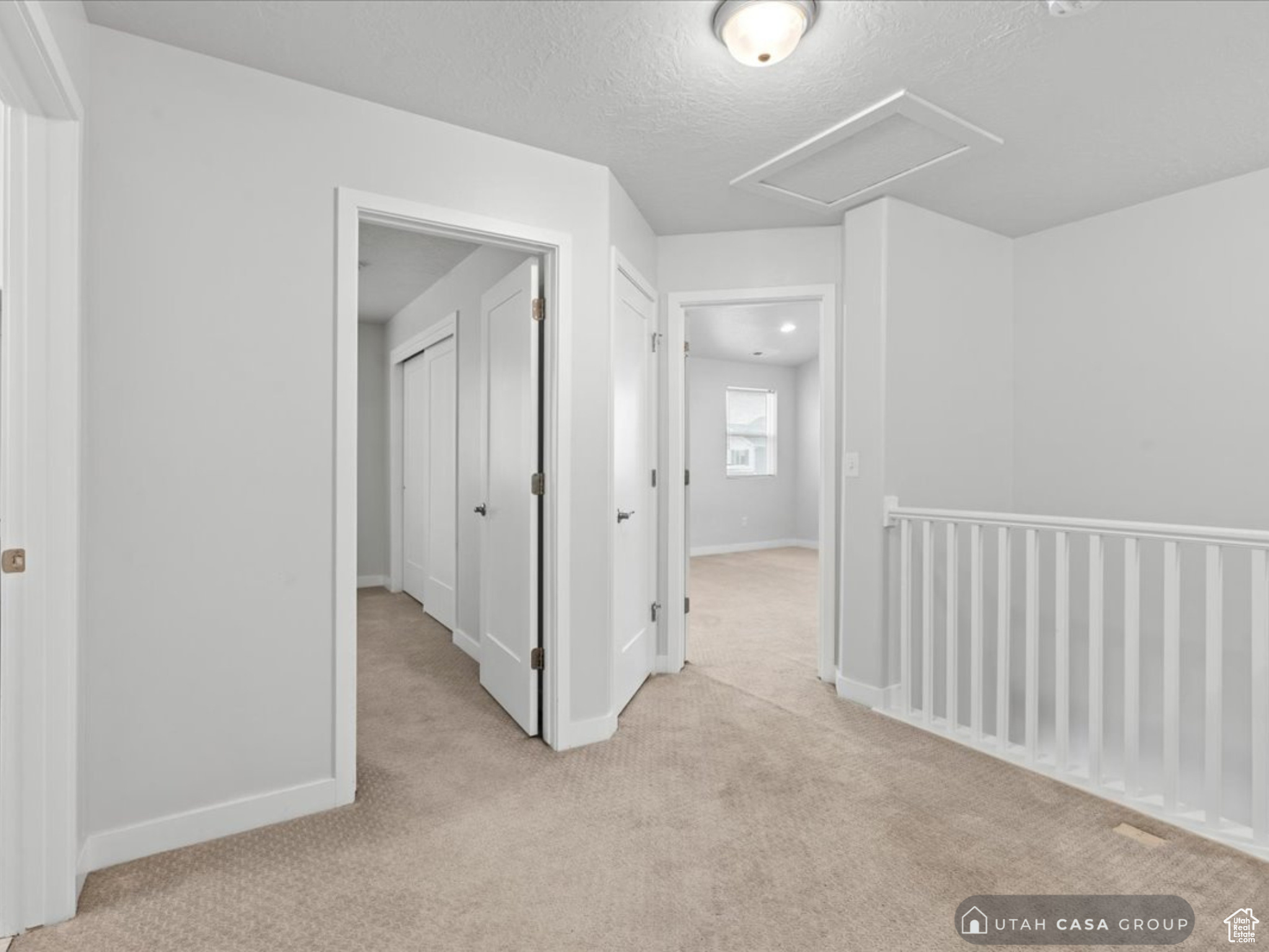 Hall featuring a textured ceiling and light colored carpet