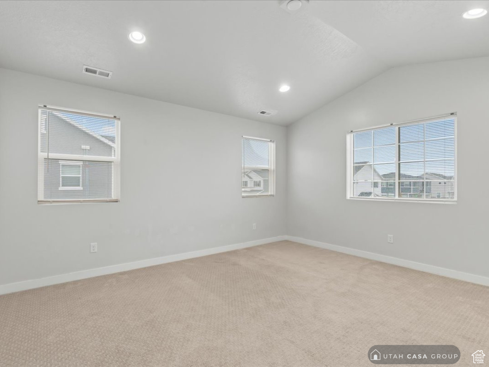 Empty room with light colored carpet and vaulted ceiling