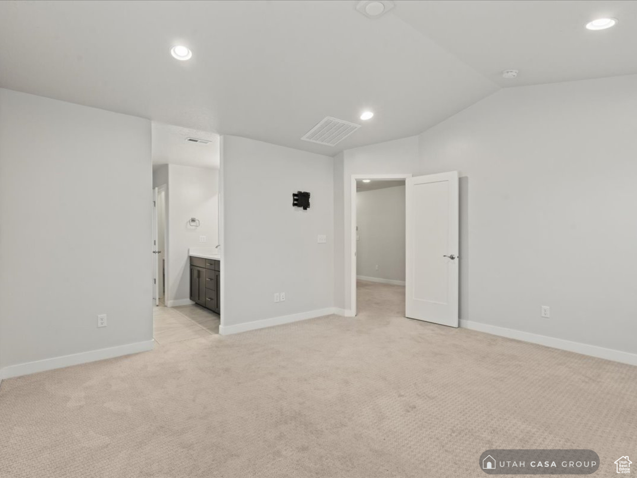 Empty room featuring light carpet and vaulted ceiling