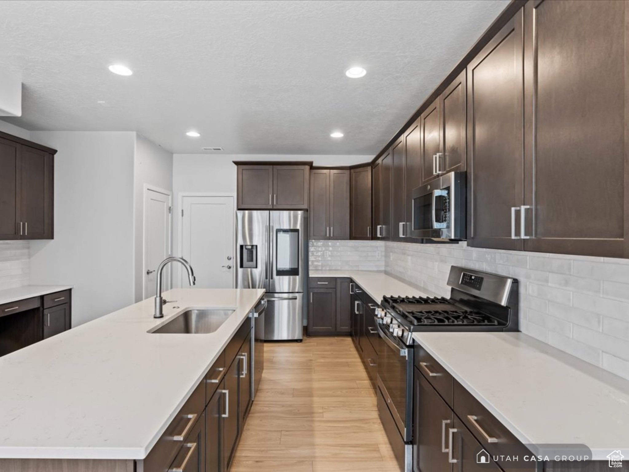 Kitchen featuring backsplash, sink, an island with sink, and stainless steel appliances