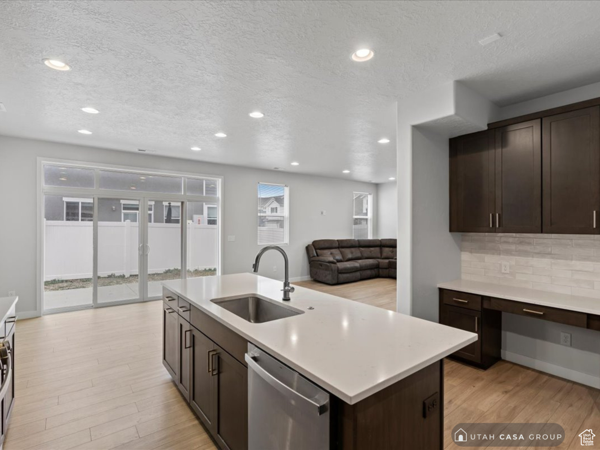 Kitchen featuring decorative backsplash, stainless steel dishwasher, a wealth of natural light, sink, and an island with sink