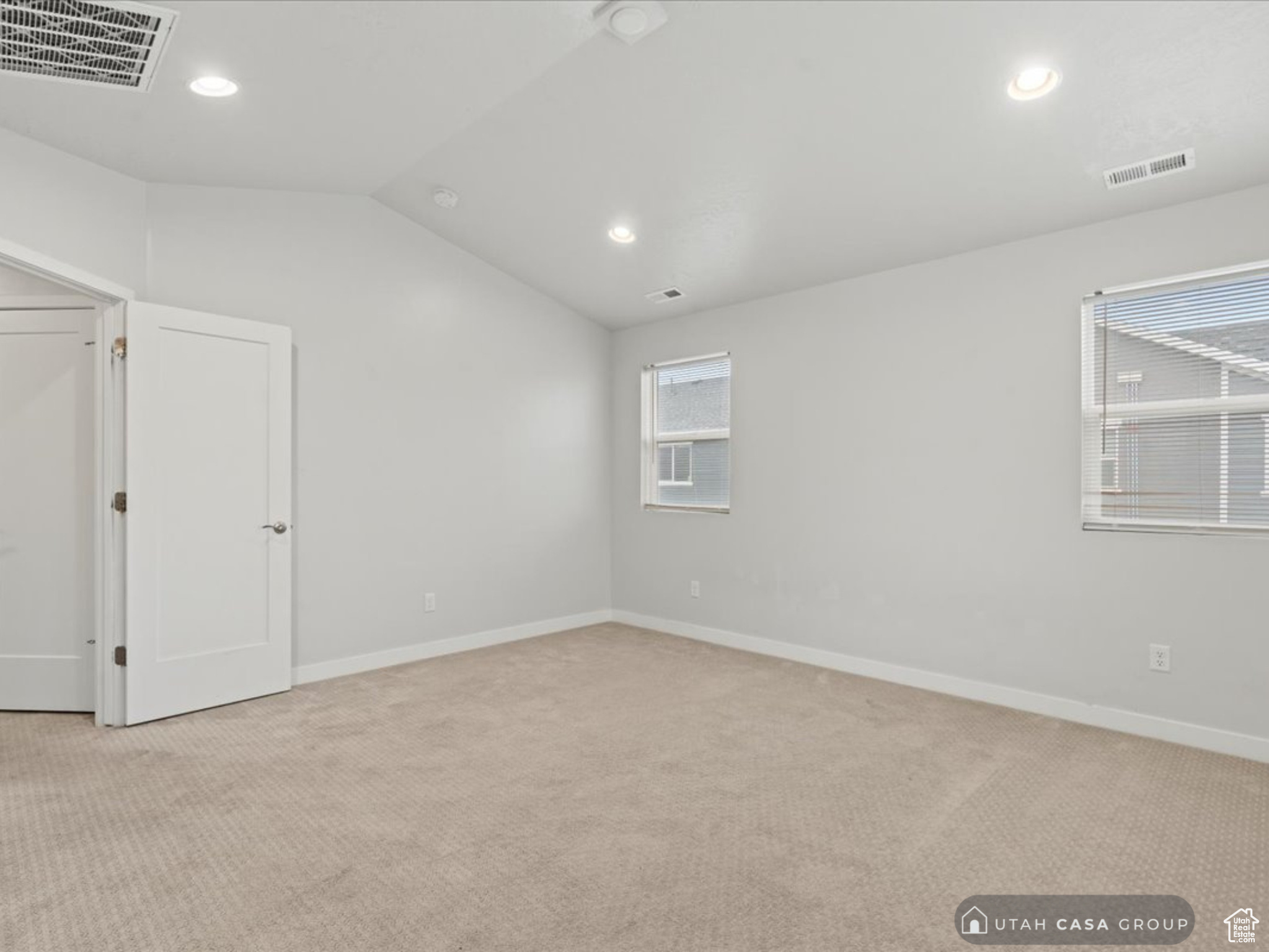 Carpeted spare room with vaulted ceiling