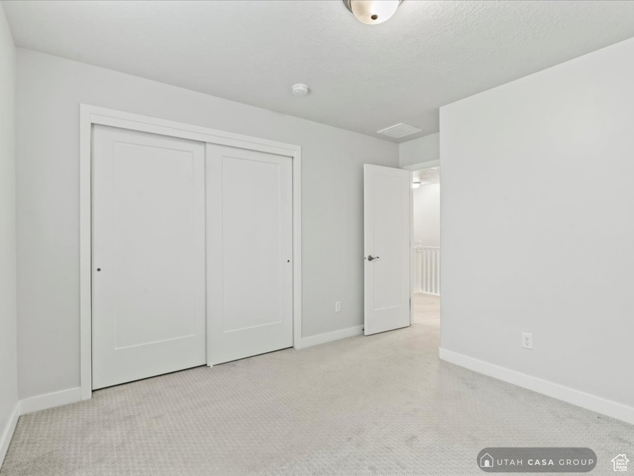 Unfurnished bedroom with light carpet and a closet