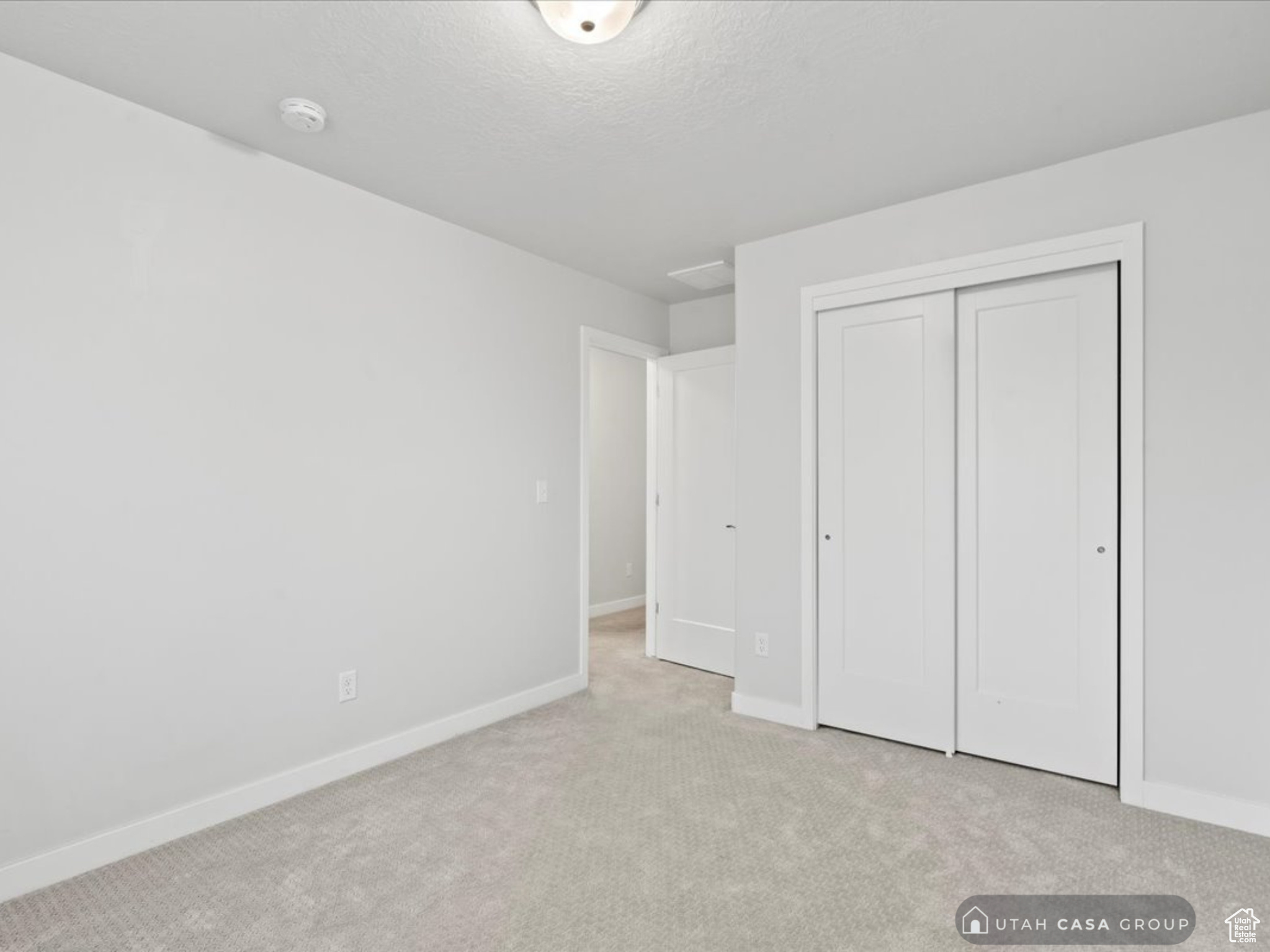 Unfurnished bedroom featuring light carpet, a closet, and a textured ceiling