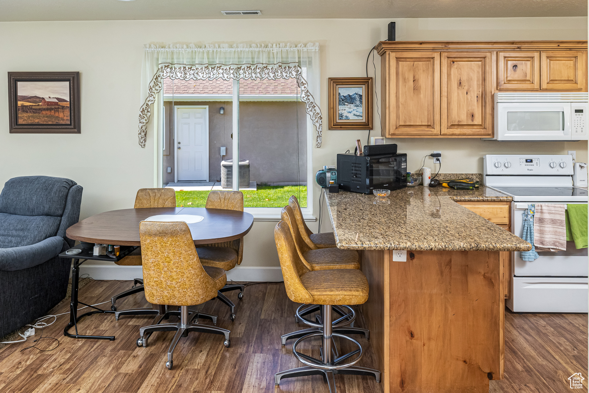 Kitchen featuring stone counters, dark hardwood / wood-style floors, and white appliances