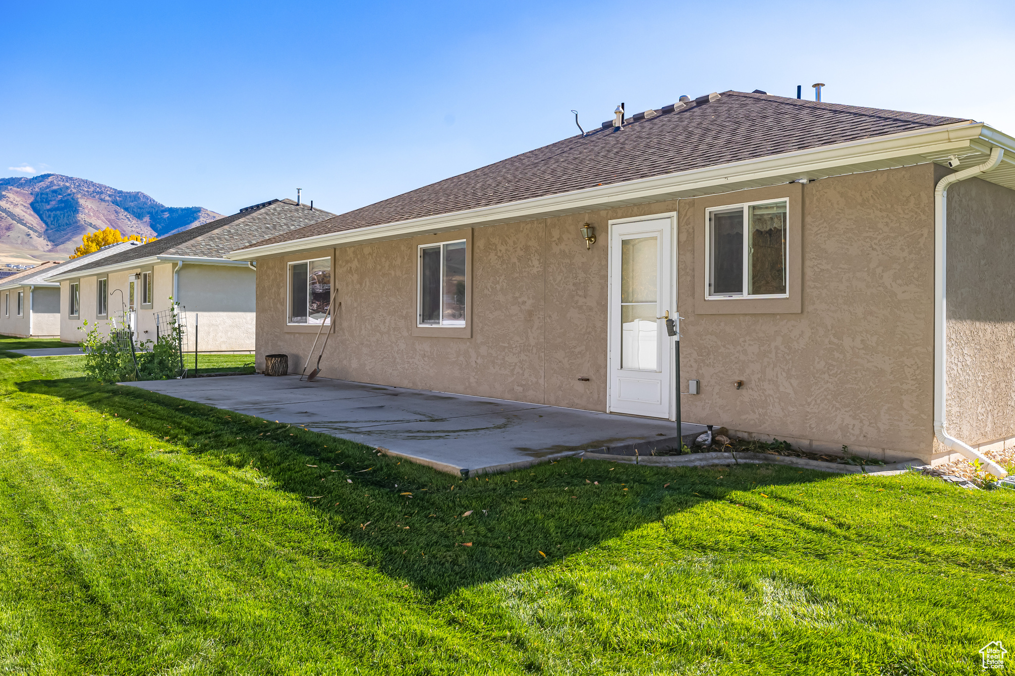 Back of property featuring a lawn, a mountain view, and a patio