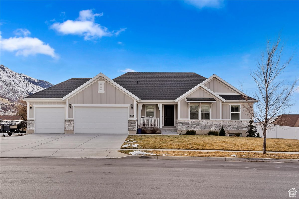 Craftsman-style house with a mountain view, a front lawn, a porch, and a garage