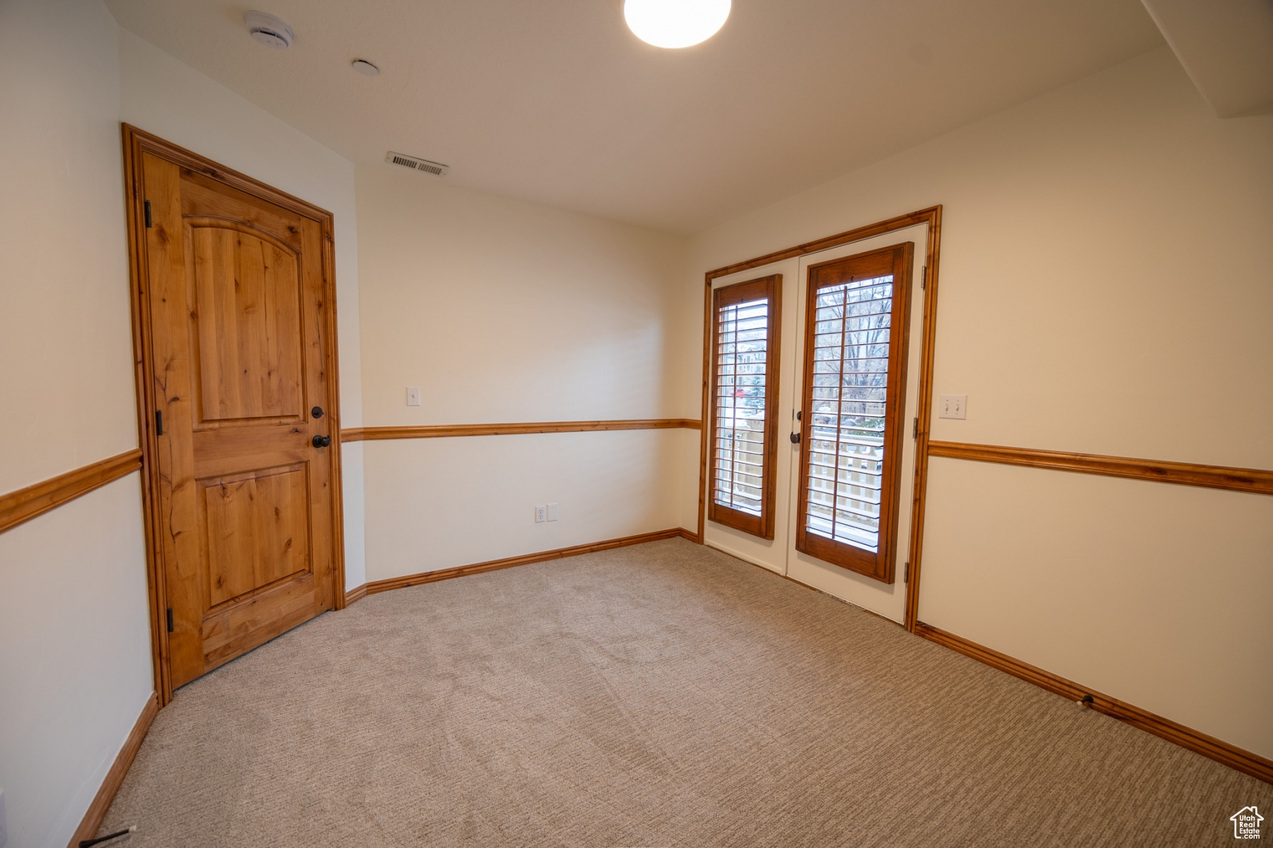 Carpeted spare room featuring french doors