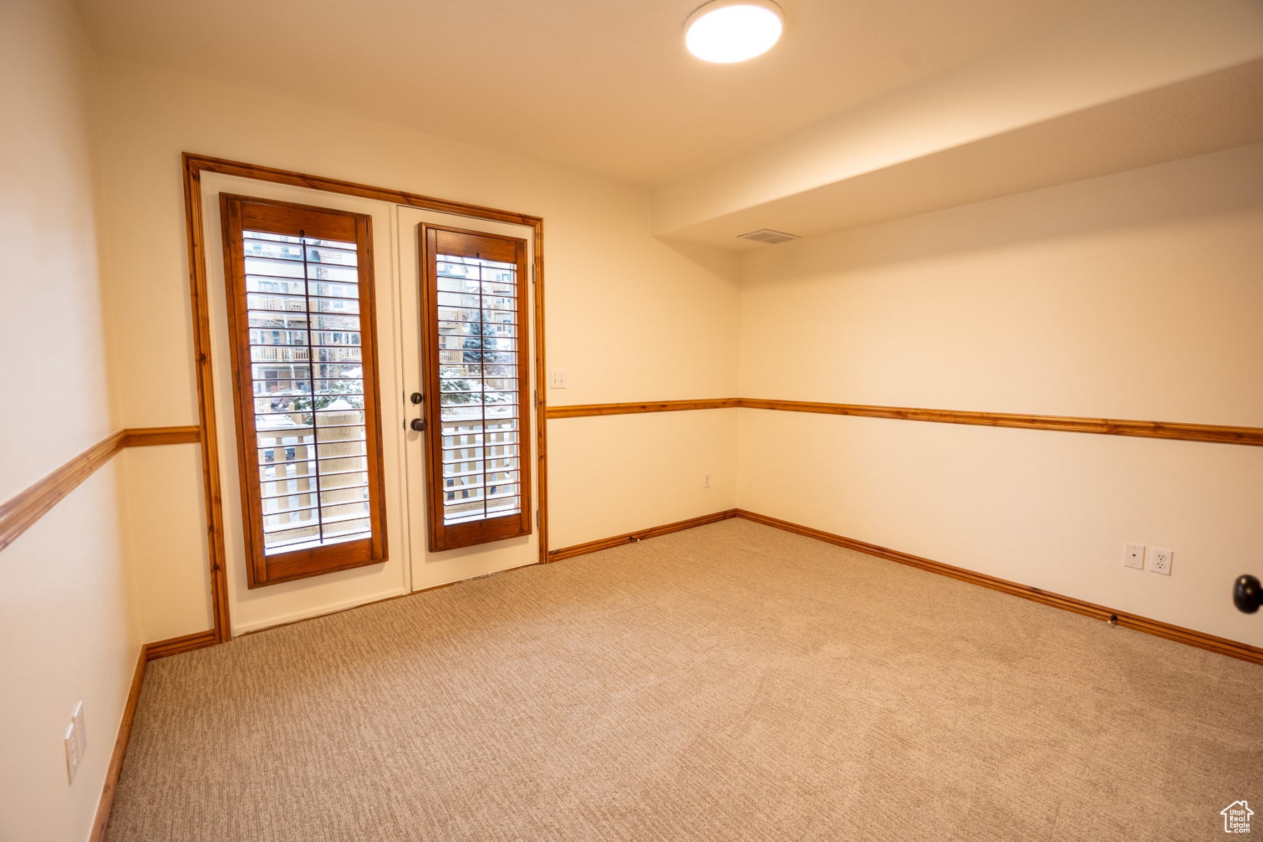 Unfurnished room featuring french doors and carpet